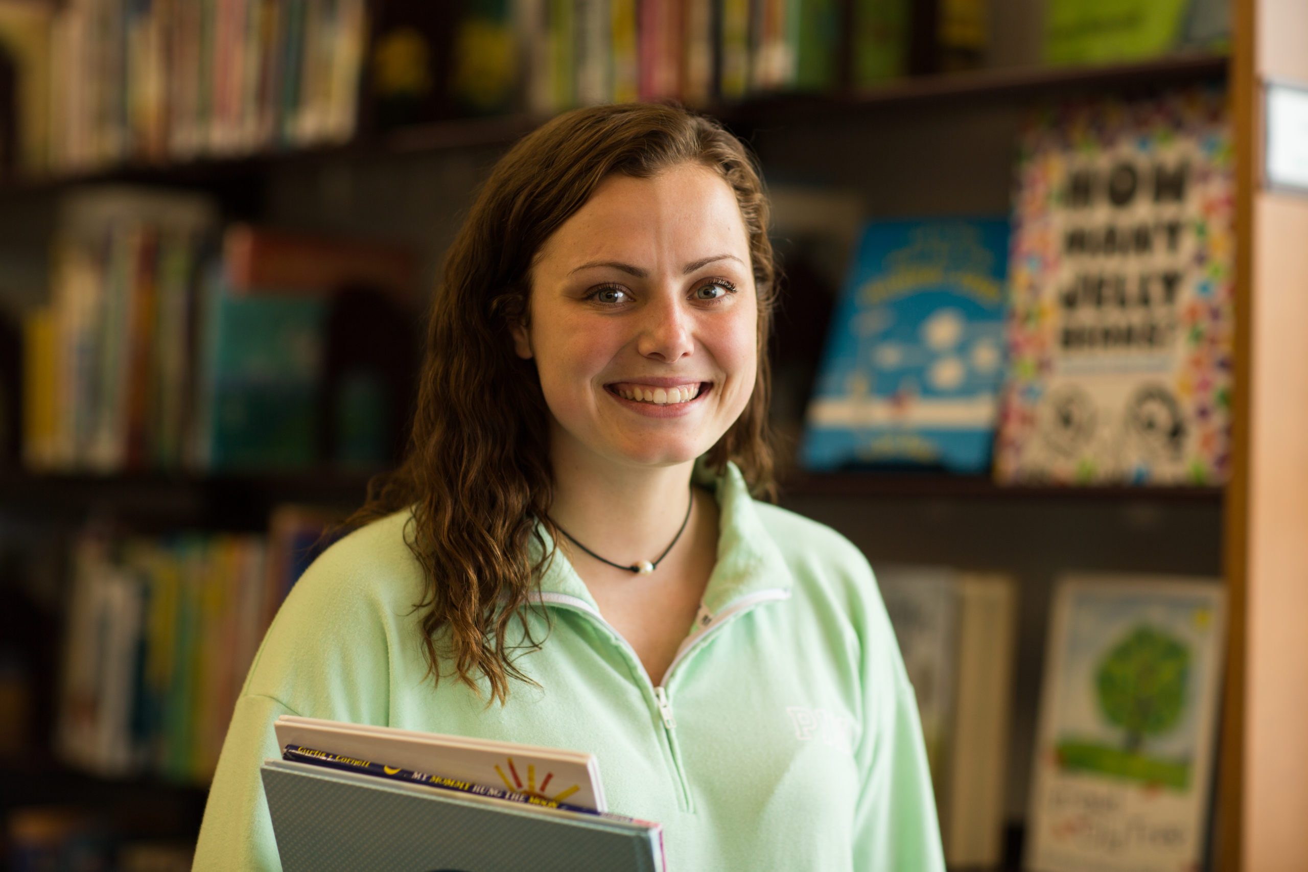 A female student in the library holding books.