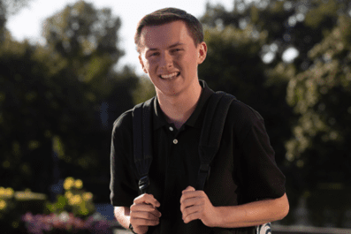 Danie smiling on campus holding backpack outside