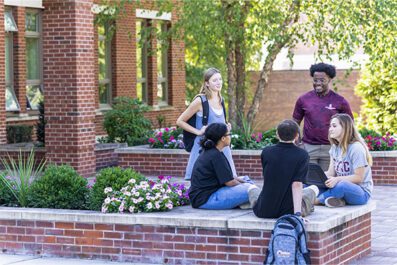 5 students outside of Borelli Hall on campus chatting