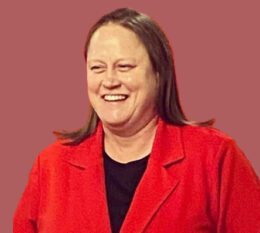 Jackie DiNuzzo smiling wearing red blazer and black shirt
