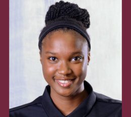 Chanelle smiling wearing black STAC Triathlon shirt with hair in a bun and white and maroon background