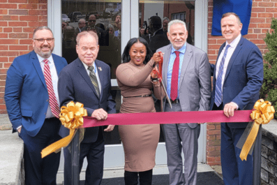President Daly, VP Mike DiBartolomeo, Ed Day, Sonya Smith, and Louis Scamardella smiling and getting ready to cut maroon ribbon in front of new SBDC sign