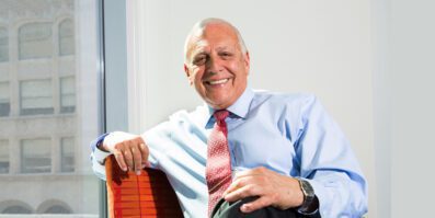 Bob Catell sitting in an office chair with office buildings in the background