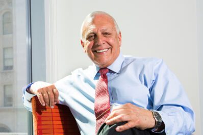 Bob Catell sitting in an office chair with office buildings in the background