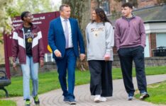 President Daly walking outside of Admissions office with three students